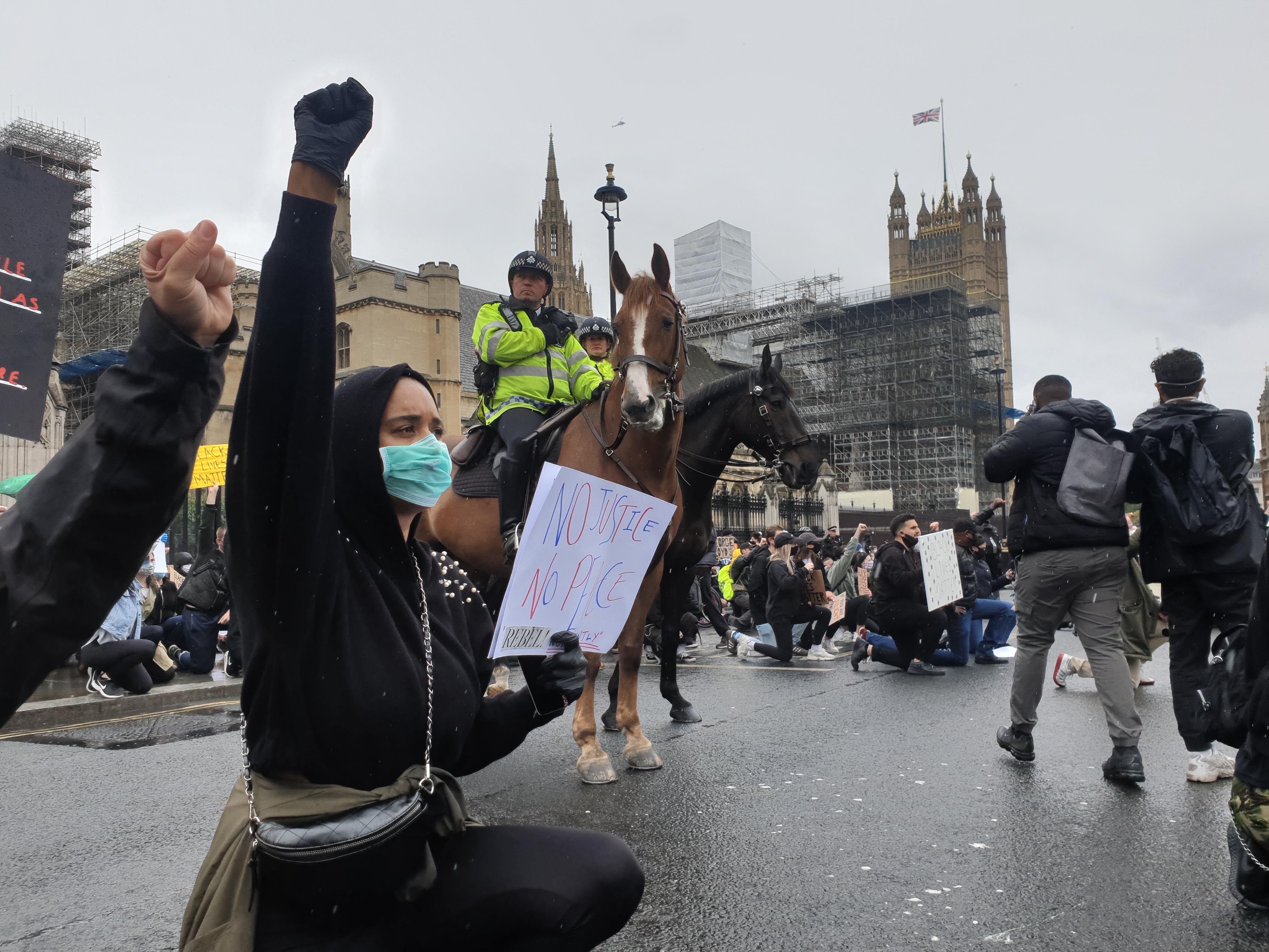 Woman at anti police brutality protest in Parliament Square takes a knee in front of Police on horseback